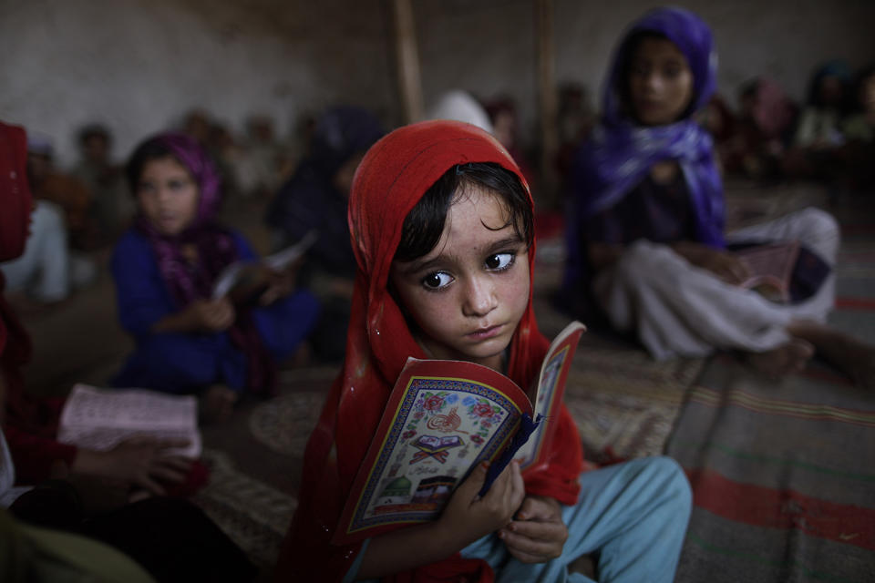 <p>Afghan refugee Aisha Daoud, 4, holds a copy of the Quran while taking part in a daily class to learn how to read verses of the Quran, at a mosque in a poor neighborhood of Rawalpindi, Pakistan, Oct. 19, 2010. (Photo: Muhammed Muheisen/AP) </p>