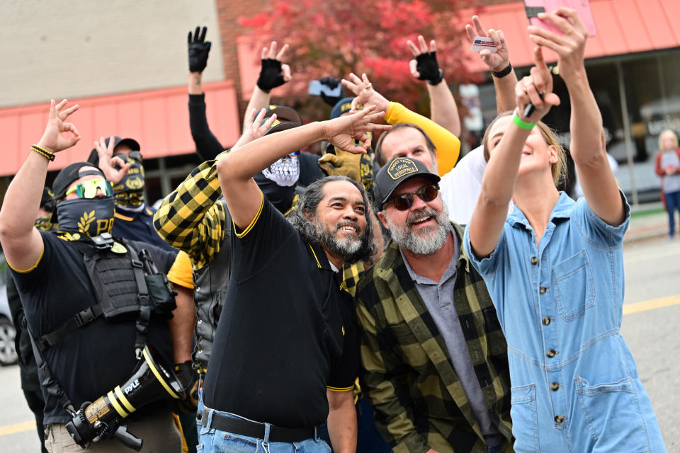 Proud Boys flash white power signs as they pose for a photo while protesting a Halloween drag show at Hugger Mugger Brewing in Sanford, Oct. 30.