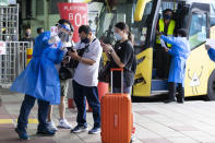 Passengers arrive from Singapore at Larkin bus station in Johor Bahru, Malaysia, Monday, Nov. 29, 2021. Malaysia and Singapore reopened their borders Monday, Nov. 29 for fully vaccinated citizens and some others, after nearly two years of closure due to the pandemic that had stranded many Malaysians working in the neighboring city-state away from their families. (AP Photo/Vincent Thian)