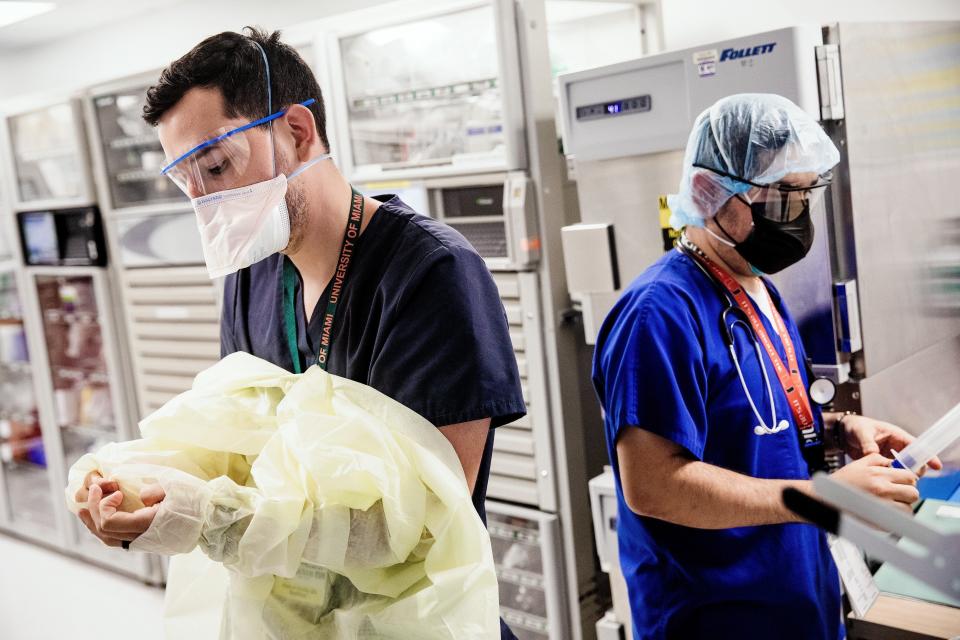 Dr. Jheison Giraldo puts on a medical gown before entering a COVID-19 patient’s room at an intensive care unit at Jackson Memorial Hospital in Miami in July.