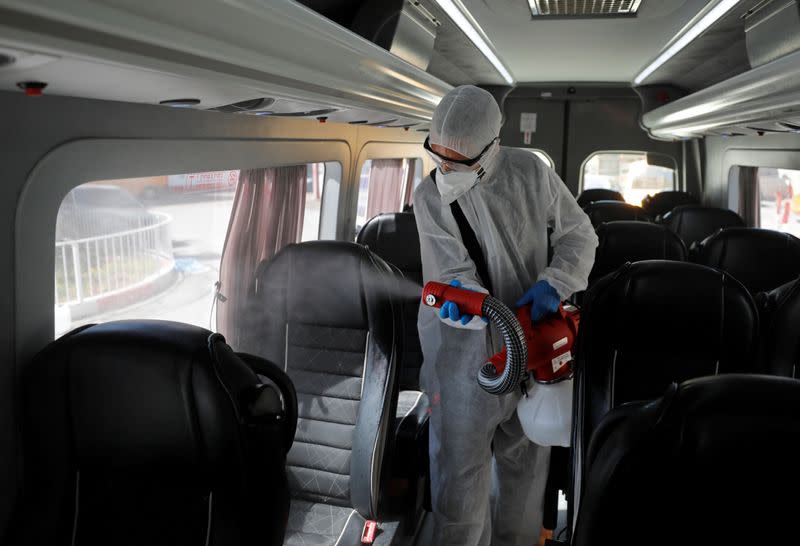 A Palestinian worker in a protective suit disinfects a bus as a preventive measure against the coronavirus in Beit Jala town in the Israeli-occupied West Bank