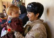 BOLDOC, AFGHANISTAN - NOVEMBER 23: (SPAIN OUT, FRANCE OUT, AFP OUT) Lance Corporal Luz Lopez, 21, a US Marine with the FET (Female Engagement Team) 1st Battalion 8th Marines, Regimental Combat team II plays with an Afghan baby girl during a village medical outreach on November 23, 2010 in Boldoc, in Helmand province , Afghanistan. There are 48 women presently working along the volatile front lines of the war in Afghanistan deployed as the second Female Engagement team participating in a more active role, gaining access where men can't. The women, many who volunteer for the 6.5 month deployment take a 10 week course at Camp Pendleton in California where they are trained for any possible situation, including learning Afghan customs and basic Pashtun language. (Photo by Paula Bronstein/Getty Images)