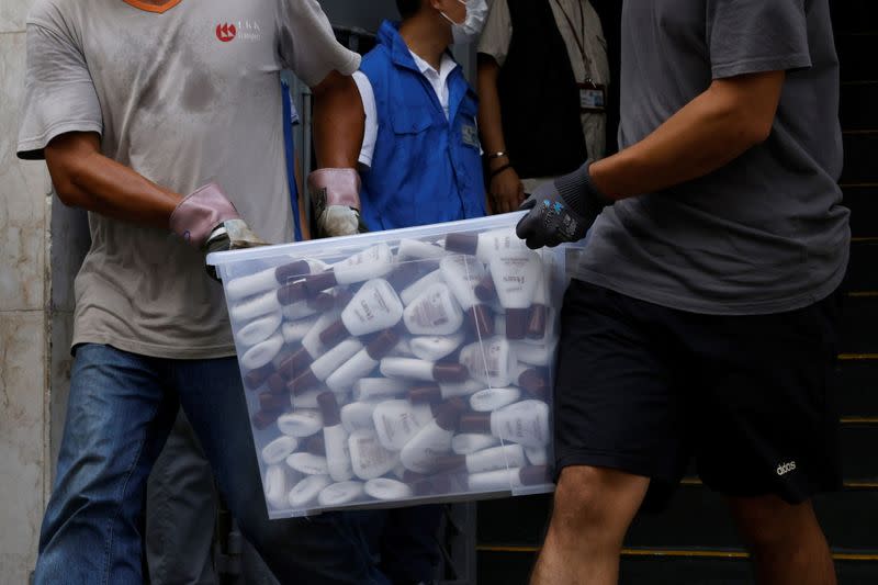 Movers collect a box of lotion after police search a warehouse of Student Politicism, in Hong Kong