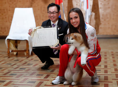 Russian figure skating gold medallist Alina Zagitova and Endo Takashi, head of the Association for the preservation of the purity of the Akito breed, pose with an Akita Inu puppy presented to her in Moscow, Russia May 26, 2018. REUTERS/Maxim Shemetov
