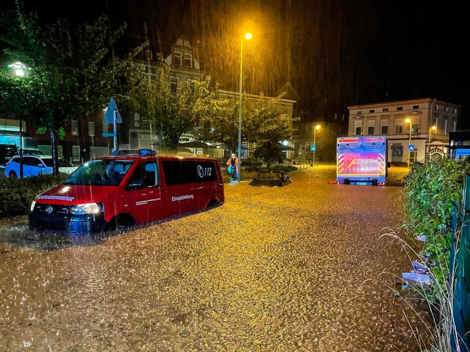 Fire engines and a car are parked on a flooded road in Hagen (Alex Talash/DPA/AP)