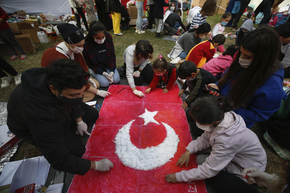 Children of families that became homeless due to the earthquake and now live in tents set up at a basketball court, paint a Turkish flag during a group activity in Izmir, Turkey, Tuesday, Nov. 3, 2020. Rescuers in the Turkish coastal city pulled a young girl out alive from the rubble of a collapsed apartment building Tuesday, four days after a strong earthquake hit Turkey and Greece. (AP Photo/Emrah Gurel)