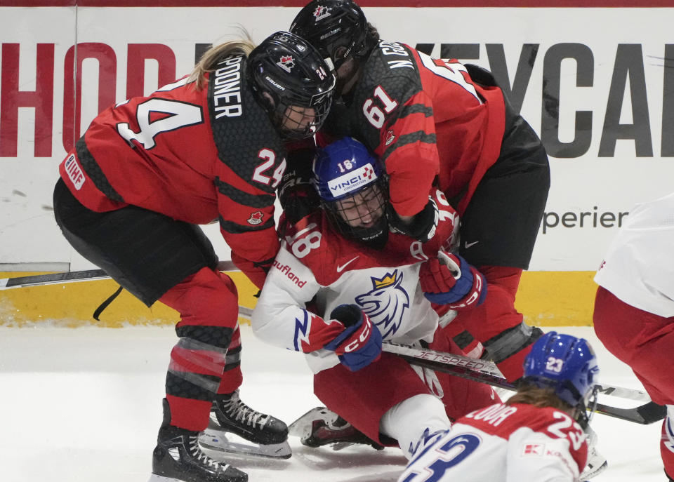 Canada's Natalie Spooner (24) and Nicole Gosling (61) take down Czechia's Michaela Pejzlova (18) during first period of a hockey match at the IIHF Women's World Championships in Utica, N.Y., Sunday, April 7, 2024.(Christinne Muschi/The Canadian Press via AP)