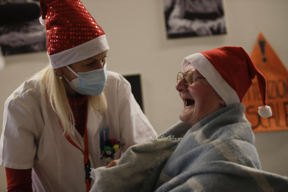 Celestina Comotti, 81, is comforted by director Maria Giulia Madaschi as she cries as she talks on a video call with Alessia Mondello a donor unrelated to her who bought and sent her a shawl as Christmas present through an organization dubbed "Santa's Grandchildren", at the Martino Zanchi nursing home in Alzano Lombardo, one of the area that most suffered the first wave of COVID-19, in northern Italy, Saturday, Dec. 19, 2020. (AP Photo/Luca Bruno)