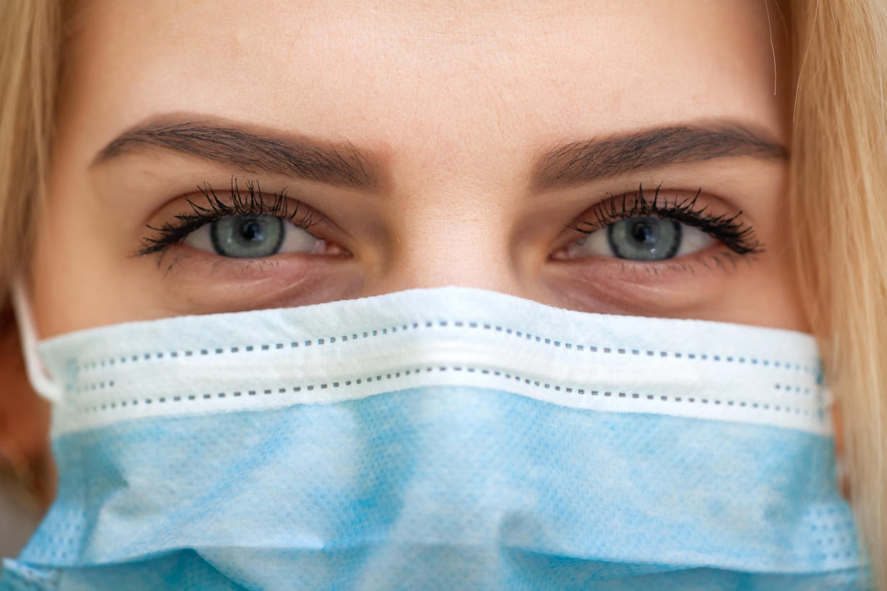 Beautiful Women In A Medical Mask. Close-up of a young woman with a surgical mask on her face against SARS-cov-2.