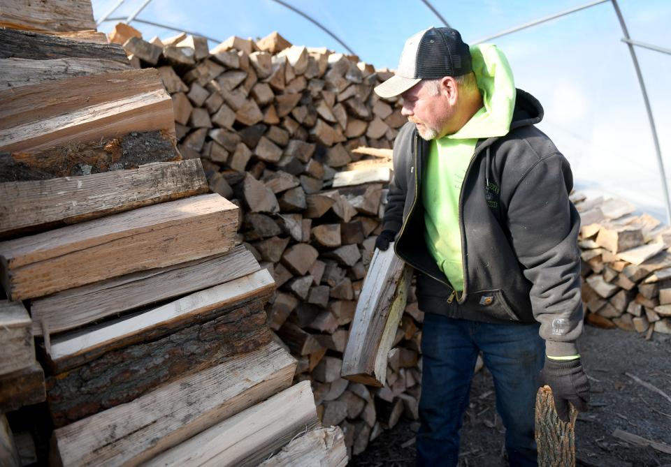 Dave West stacks wood for winter as the Christmas season gets underway at Planted Roots Garden Center in Plain Township.