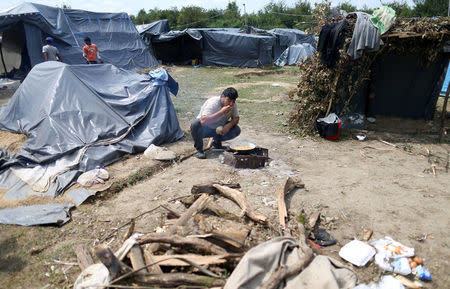 A migrant eats a meal in front of a tent in a makeshift tent camp in Velika Kladusa, Bosnia and Herzegovina, July 26, 2018. REUTERS/Dado Ruvic