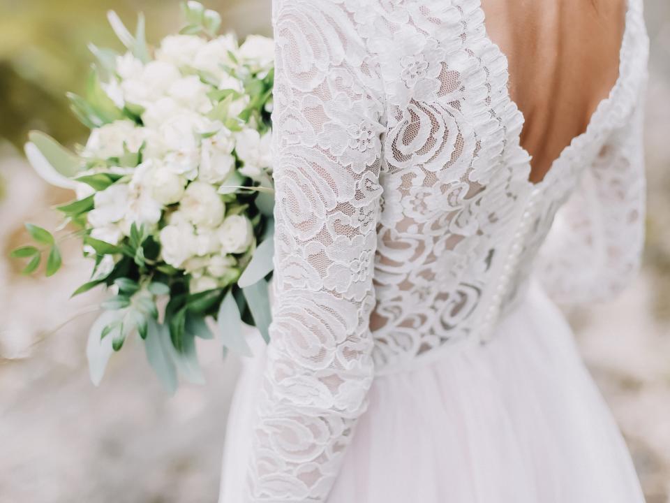 Bride in lace wedding gown with white bouquet of flowers