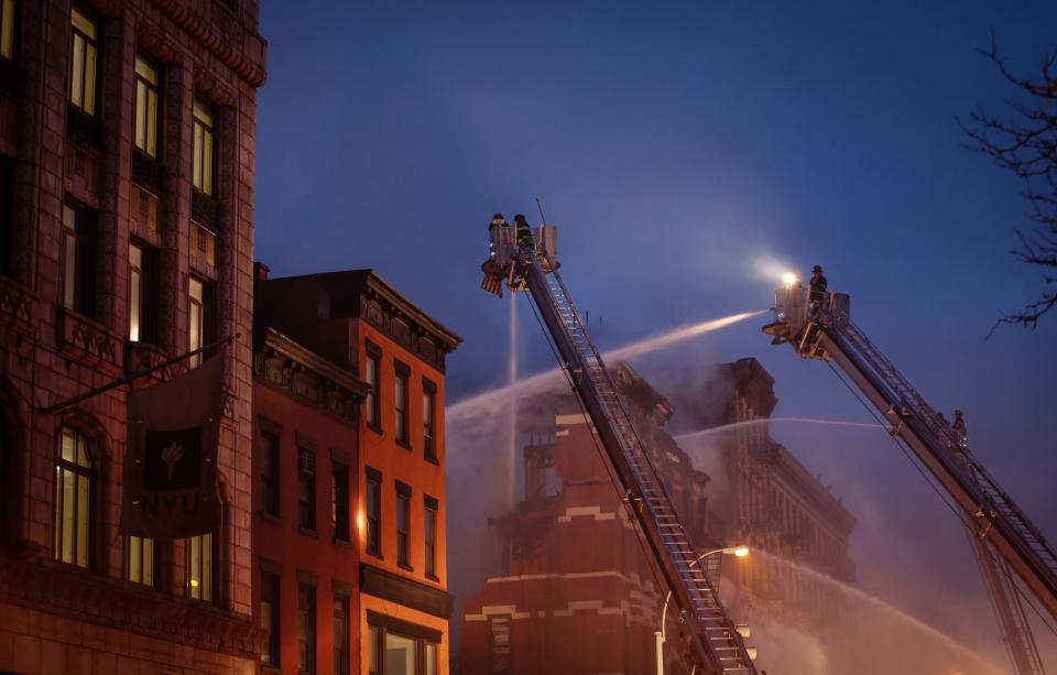 NEW YORK, NY - MARCH 26: New York City Fire Department personel try to extinguish the fire broke out after a massive explosion in a building on 2nd Avenue of Manhattan's East Village on March 26, 2015 in New York, United States. Officials have reported that two buildings partially collapsed and engulfed in flames and at least 12 people were injured but it is unclear if anyone was trapped inside either building. (Photo by Cem Ozdel/Anadolu Agency/Getty Images)