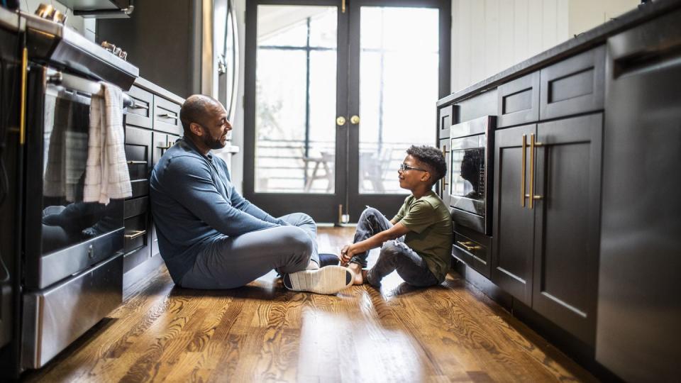 father talking with tween son in residential kitchen