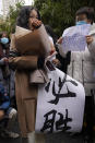 Zhou Xiaoxuan, left, holds a banner which reads "Must Win" as she arrives at a courthouse in Beijing, Wednesday, Dec. 2, 2020. Zhou, a Chinese woman who filed a sexual harassment lawsuit against a TV host, told dozens of cheering supporters at a courthouse Wednesday she hopes her case will encourage other victims of gender violence in a system that gives them few options to pursue complaints. (AP Photo/Andy Wong)