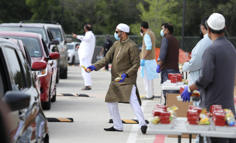 Organizers hand out treats during a drive through Eid al-Fitr celebration outside a closed mosque in Plano, Texas, Sunday, May 24, 2020. Many Muslims in America are navigating balancing religious and social rituals with concerns over the virus as they look for ways to capture the Eid spirit this weekend. (AP Photo/LM Otero)