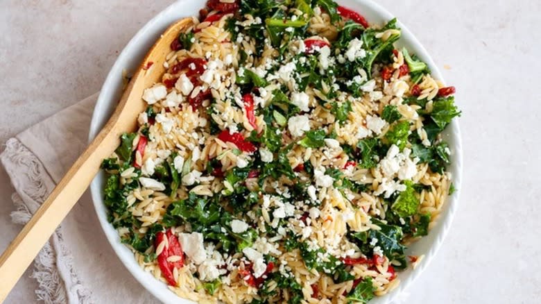 Top-down view of orzo salad with feta and kale in a white bowl