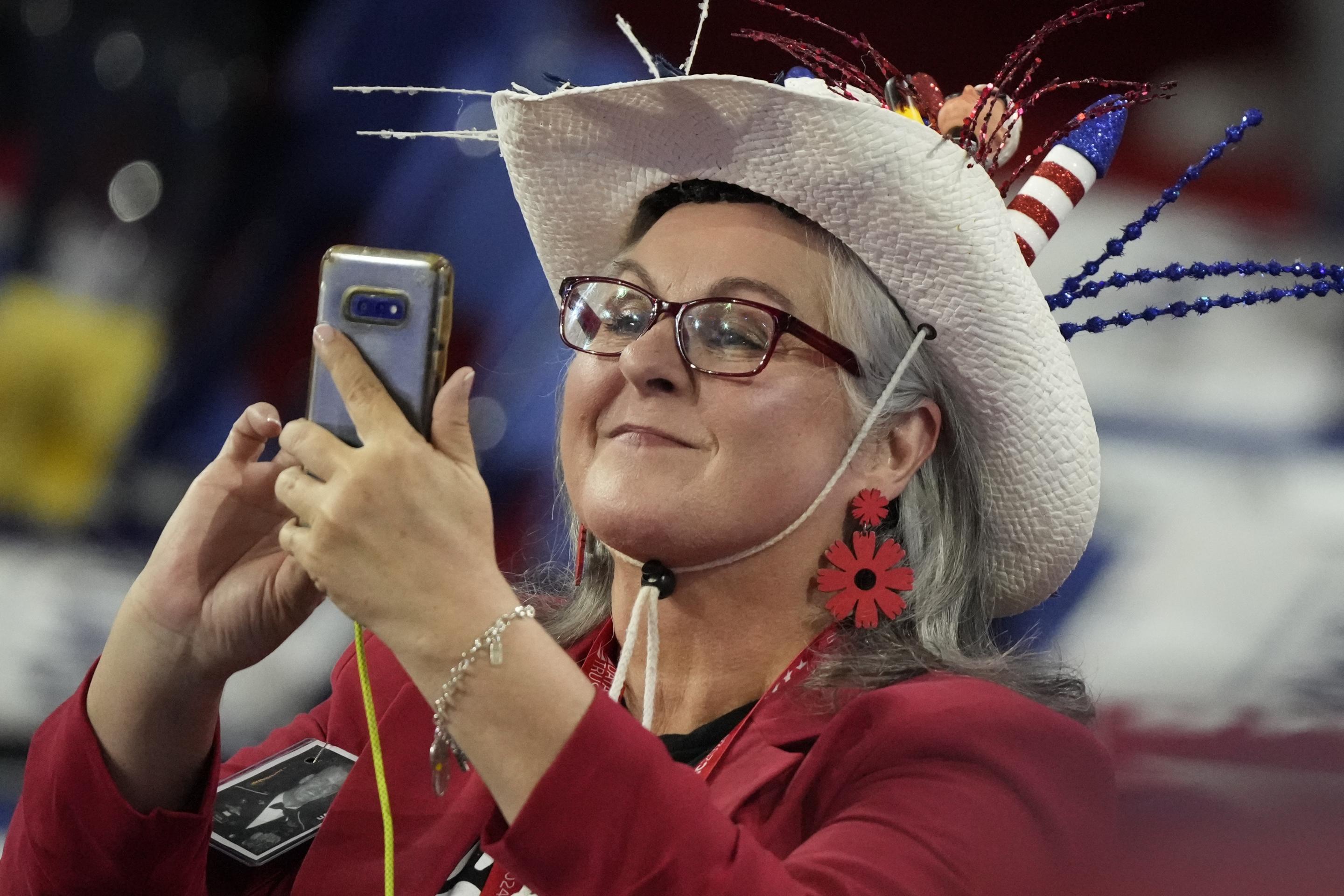 A hat-wearing delegate takes a picture before the start of the convention. (Matt Rourke/AP)