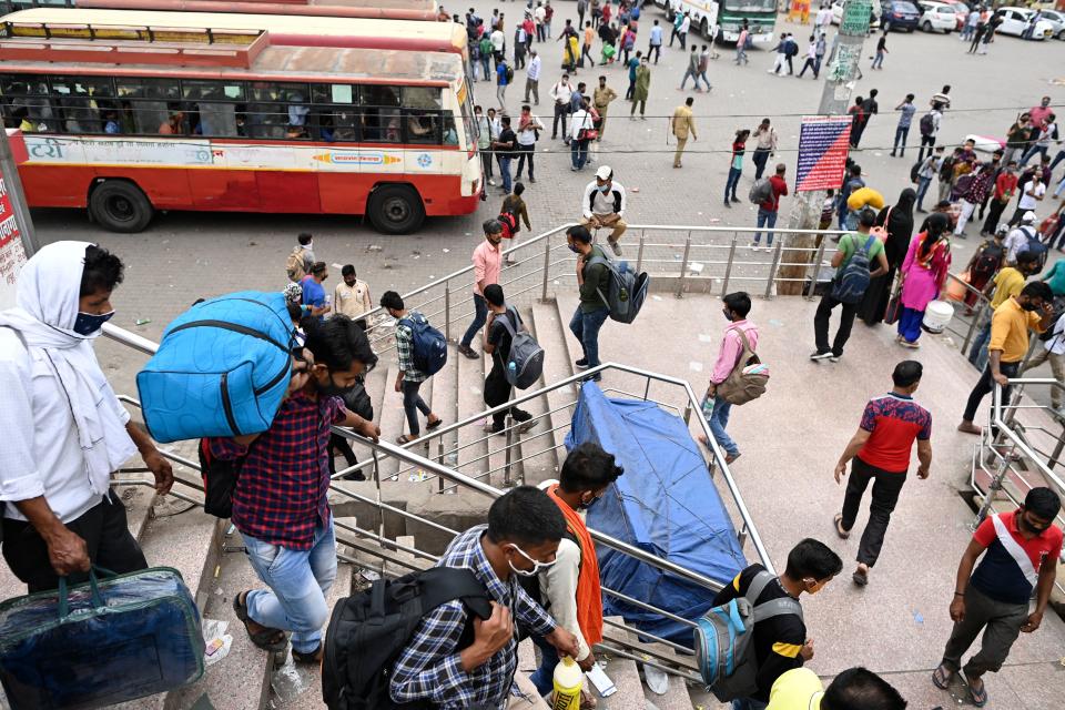 People arrive at a bus station in New Delhi on April 20, 2021, to leave for their native places as India battles a record-breaking spike in Covid-19 coronavirus infections that has forced the capital into a week-long lockdown. (Photo by Sajjad HUSSAIN / AFP) (Photo by SAJJAD HUSSAIN/AFP via Getty Images)