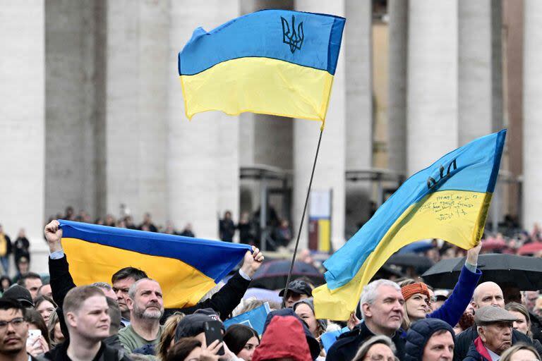 La gente ondea banderas ucranianas en la plaza de San Pedro mientras el Papa Francisco se dirige a la multitud durante su oración del Ángelus dominical el 10 de marzo de 2024 en el Vaticano