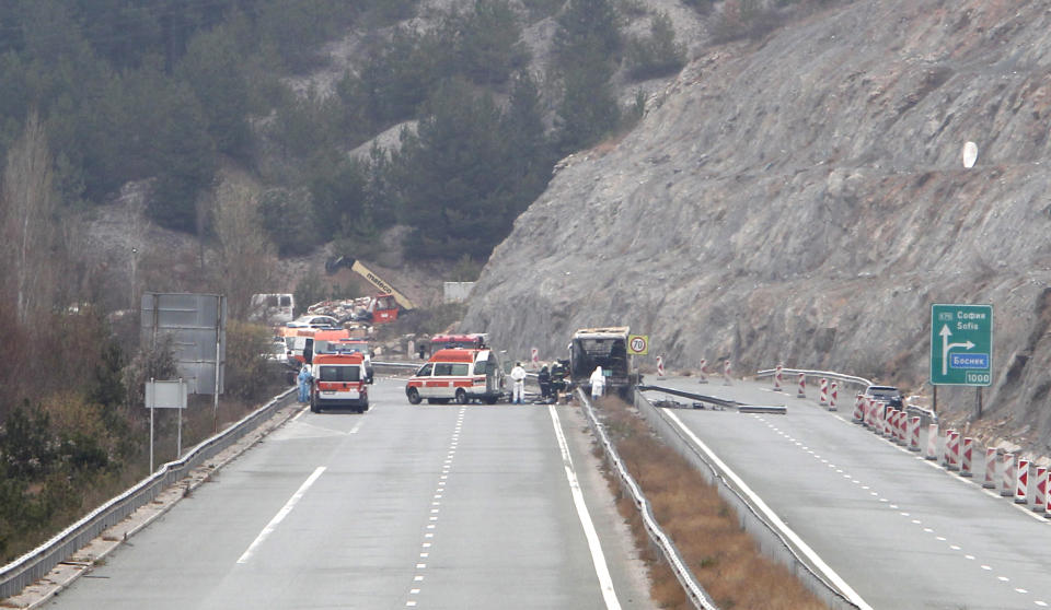 Firefighters and forensic workers inspect the scene of a bus crash on a highway near the village of Bosnek, western Bulgaria, Tuesday, Nov. 23, 2021. A bus carrying tourists back to North Macedonia crashed and caught fire in western Bulgaria early Tuesday, killing at least 45 people, including a dozen children, authorities said. (AP Photo/Boris Grdanoski)