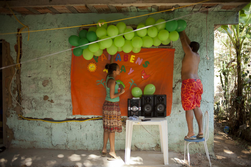 In this Sept. 15, 2012 photo, Thiago Dutra, right, helps hang balloons for the birthday of his wife Thayara Domiciano, left, at their home in the Quilombo Sacopa in Rio de Janeiro, Brazil. Quilombos are communities founded by escaped slaves or their descendents, and in Sacopa, the community is trying to save the grouping of brick houses and shacks nestled in the lush foilage of Brazil’s coastal rainforest where families have made their home for more than century but never legally owned. (AP Photo/Victor R. Caivano)