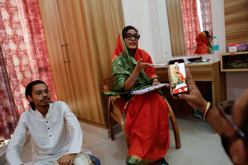 Neha Singh Rathore, 27, a folk singer and social media content creator, sings a song while her husband and member of her team, Himanshu Singh, records the songs on a mobile phone at their room in a hotel in Noida
