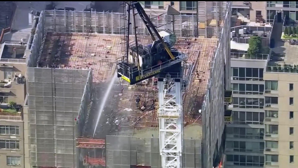 Emergency responders are on the scene after a large construction crane caught fire in Manhattan on Wednesday, July 26, 2023 in New York. The crane caught fire and its arm hit a building as it crashed to the street below. (WABC via AP)