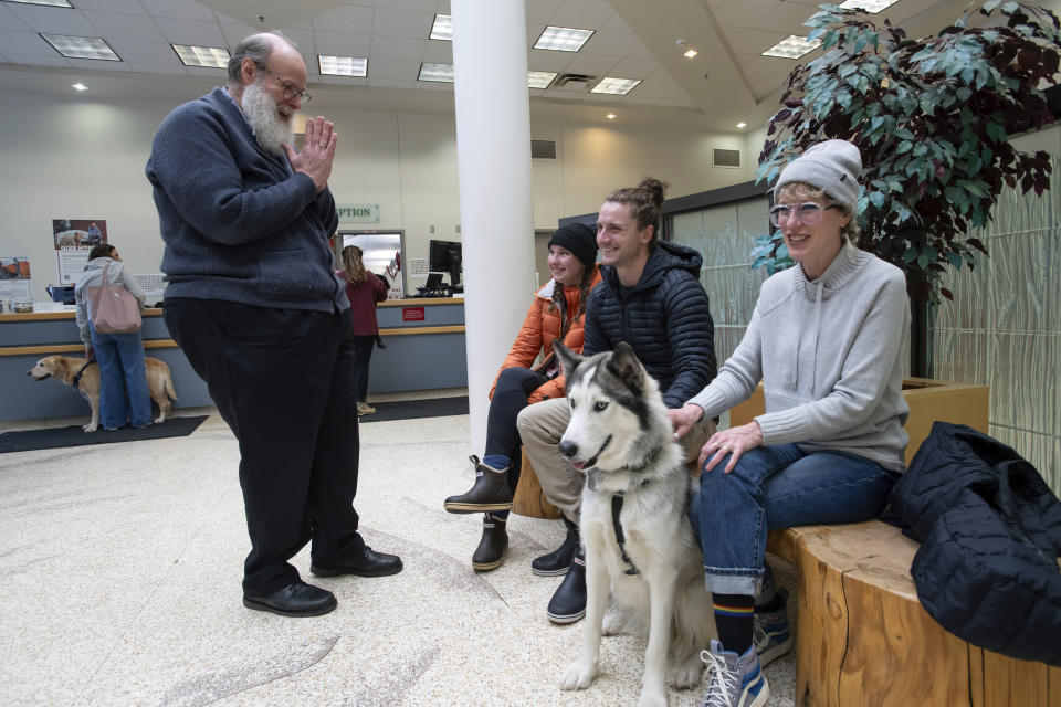 In this image provided by WSU College of Veterinary Medicine, Scott Campbell, left, the veterinary chaplain at Washington State University's College of Veterinary Medicine, visits with Olivia and Phinehas Lampman, center, owners of Goose, a Husky mix dog, as Phinehas' mother and WSU Honors College Associate Professor Annie Lampman, right, looks on, Wednesday, Jan. 10, 2024, in the lobby of the Veterinary Teaching Hospital in Pullman, Wash. (Ted S. Warren/WSU College of Veterinary Medicine via AP)