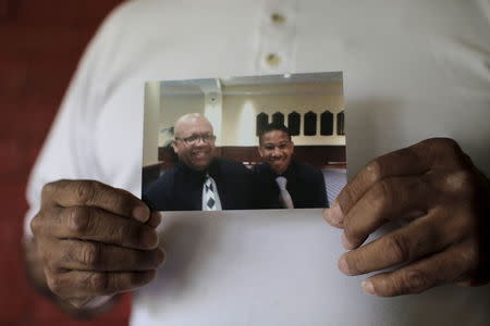 Ronald Cook, holds a photograph of him and his 20-year-old grandson Devin Cook, who was killed last year, at his home in Baltimore, Maryland July 24, 2015. REUTERS/Carlos Barria