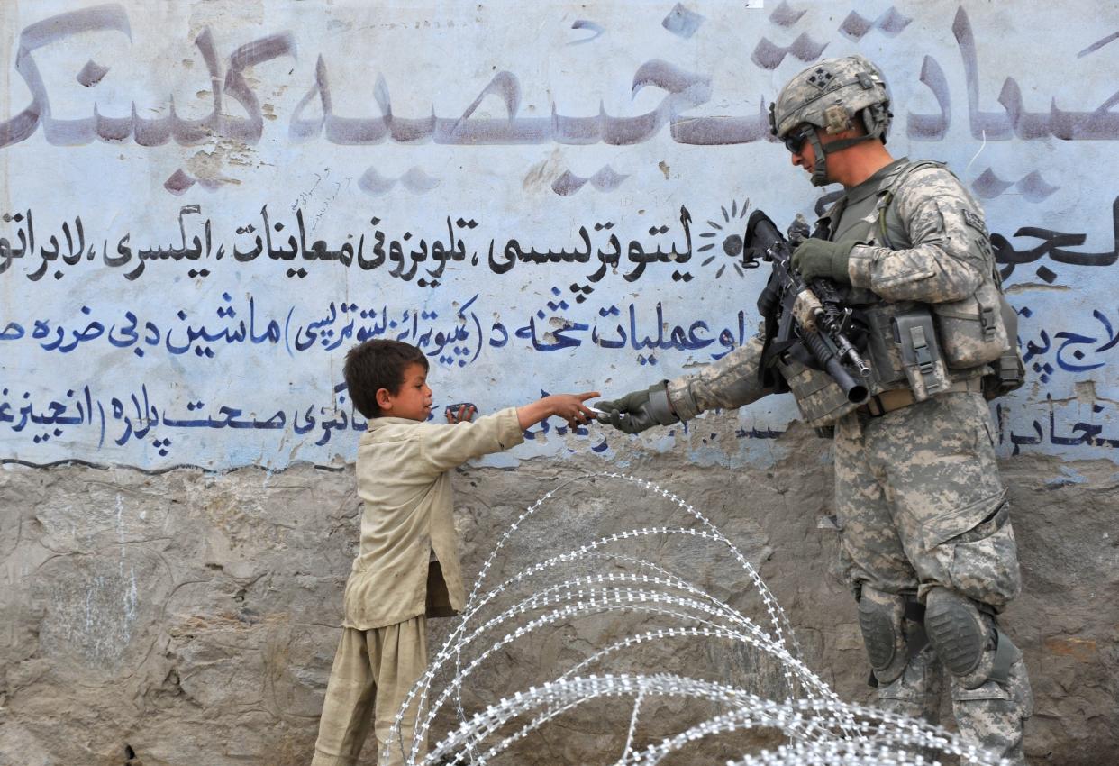 <p>US soldier  presents a gift to an Afghan child during a patrol at Khogiani in Langarhar in 2010</p> (AFP)