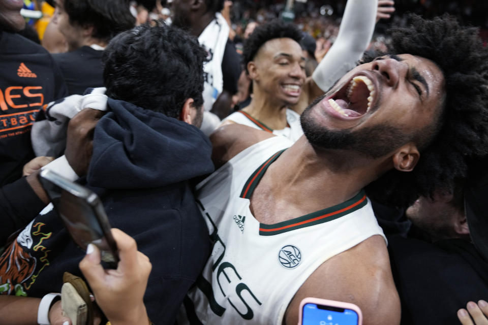 Surrounded by fans who rushed the court, Miami forward Norchad Omier shouts as Miami players celebrate after defeating Pittsburgh in an NCAA college basketball game to win a share of the Atlantic Coast Conference regular-season championship, Saturday, March 4, 2023, in Coral Gables, Fla. Miami shares the title with Virginia. (AP Photo/Rebecca Blackwell)