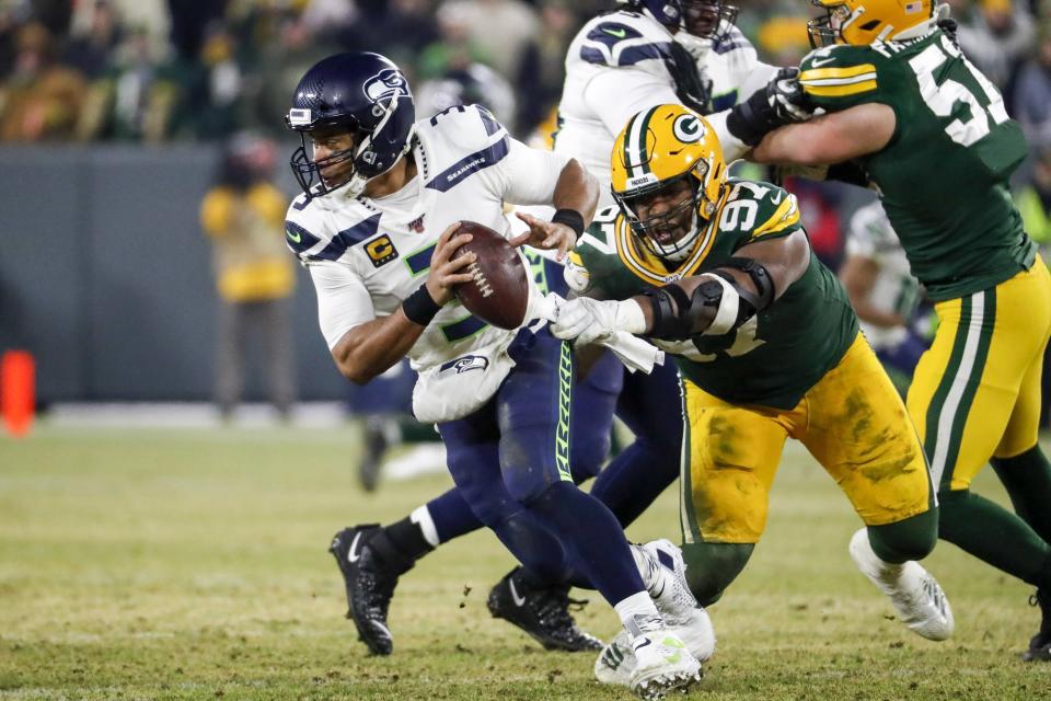 File-Seattle Seahawks' Russell Wilson tries to get away from Green Bay Packers' Kenny Clark during the first half of an NFL divisional playoff football game Sunday, Jan. 12, 2020, in Green Bay, Wis. Clark said earlier this month of the Packers’ facility, “You walk in here, you get tested, there’s sanitizers everywhere. You know, the masks, everything that we’re doing, they’re serious about getting us ready to be able to play and keeping us healthy.” (AP Photo/Matt Ludtke, File)