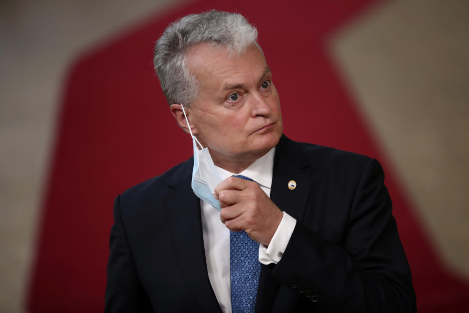 Lithuania's President Gitanas Nauseda takes off his protective face mask as he prepares to make a statement on arrival for an EU summit at the European Council building in Brussels, Friday, July 17, 2020. Leaders from 27 European Union nations meet face-to-face on Friday for the first time since February, despite the dangers of the coronavirus pandemic, to assess an overall budget and recovery package spread over seven years estimated at some 1.75 trillion to 1.85 trillion euros. (AP Photo/Francisco Seco, Pool)