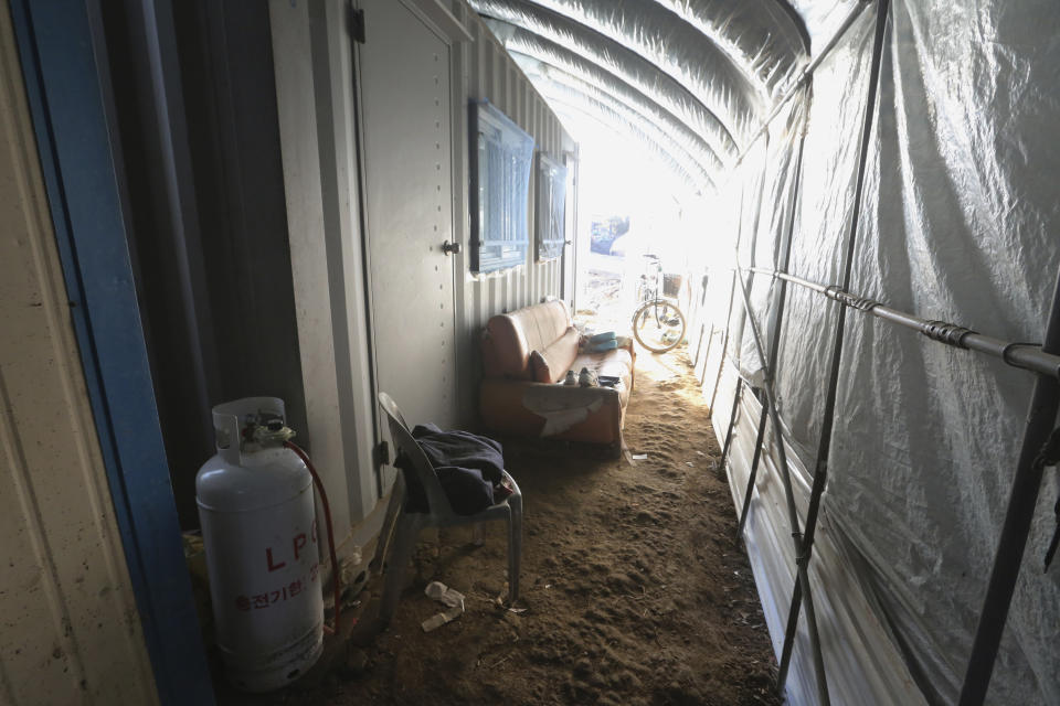 A propane gas tank, chair and sofa are placed next to a shipping container, a makeshift home for migrant workers at a farm in Pocheon, South Korea on Feb. 8, 2021. Workers often are crammed in shipping containers or flimsy, poorly ventilated huts. (AP Photo/Ahn Young-joon)