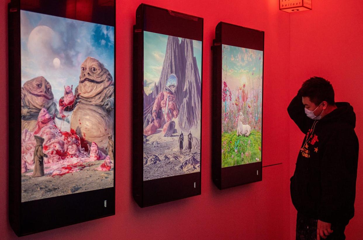 <span class="caption">NFTs can be used to prove who created and who owns digital items like these images by the artist Beeple shown at an exhibition in Beijing.</span> <span class="attribution"><a class="link " href="https://www.gettyimages.com/detail/news-photo/man-looks-at-digital-paintings-by-us-artist-beeple-at-a-news-photo/1231940889?adppopup=true" rel="nofollow noopener" target="_blank" data-ylk="slk:Nicolas Asfouri/AFP via Getty Images;elm:context_link;itc:0;sec:content-canvas">Nicolas Asfouri/AFP via Getty Images</a></span>