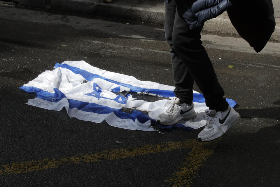 A demonstrator walks on an Israeli flag during a banned protest in support of Palestinians in the Gaza Strip, Saturday, May, 15, 2021 in Paris. Marches in support of Palestinians in the Gaza Strip were being held Saturday in a dozen French cities, but the focus was on Paris, where riot police got ready as organizers said they would defy a ban on the protest. (AP Photo/Michel Euler)