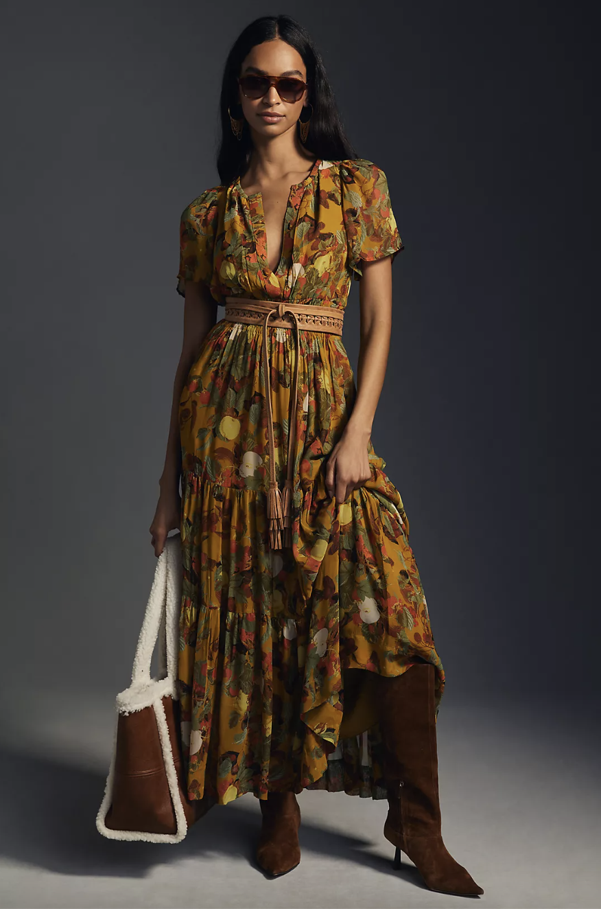 model wearing sunglasses, brown boots, and mustard yellow printed The Somerset Maxi Dress: Chiffon Edition in yellow motif (Photo via Anthropologie)