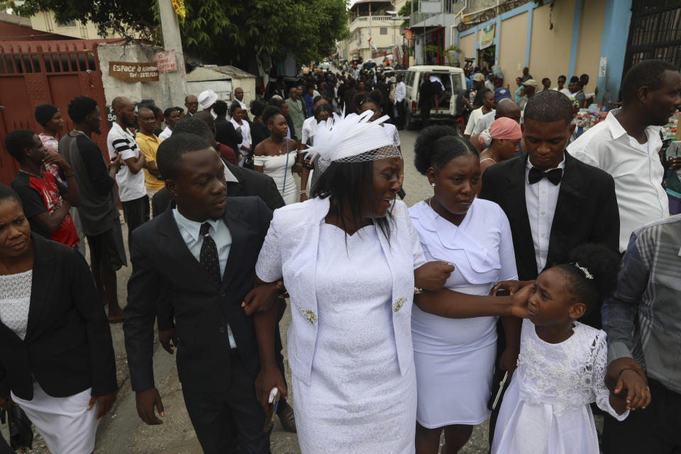 Eunide Majeur Montis, the wife of slain mission director Judes Montis, reaches out to comfort her daughter Elisabeth after they attended his funeral service in Port-au-Prince, Haiti, Tuesday, May 28, 2024. The service also honored the lives of Davy and Natalie Lloyd, a married couple in their early 20s who were with Montis when gunmen ambushed them on Thursday night, May 23, as they left a youth group activity held at a local church. (AP Photo/Odelyn Joseph)