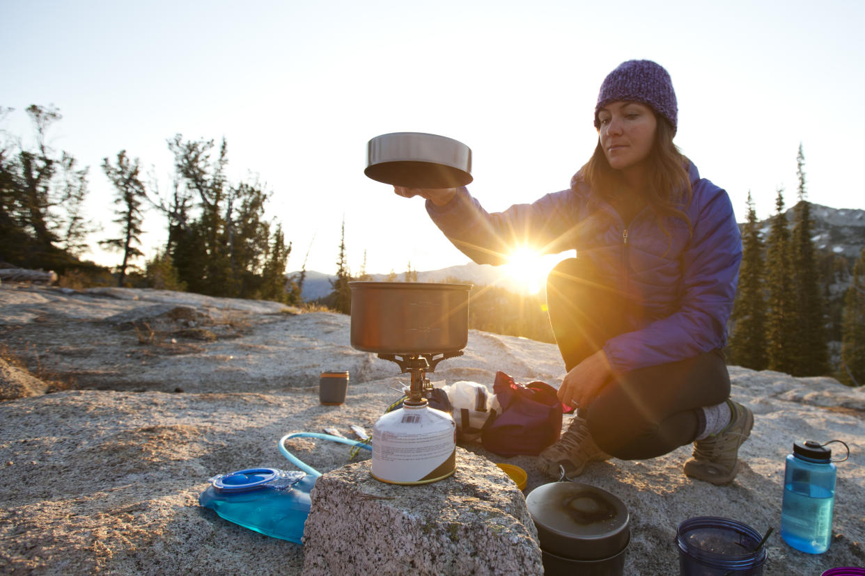  How much fuel to bring backpacking: hiker cooking at sunset. 