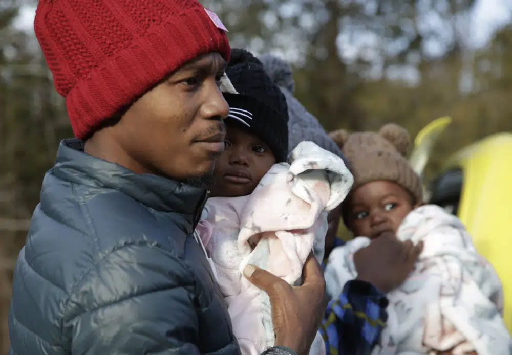 Haitian migrant Gerson Solay, 28, carries his daughter, Bianca, as he and his family cross into Canada at the non-official Roxham Road border crossing north of Champlain, N.Y., on Friday, March 24, 2023. (AP Photo/Hasan Jamali)