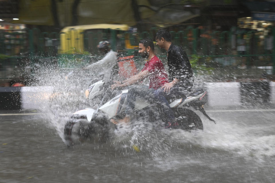 A motorcyclist drives through a water logged street during a heavy downpour in New Delhi, India, Sunday, July 9, 2023. (AP Photo/Manish Swarup)