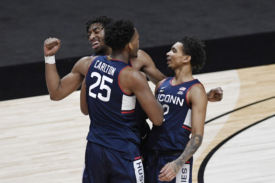 Connecticut's Josh Carlton (25) celebrates with Isaiah Whaley, rear, and James Bouknight right, during the first half of an NCAA college basketball game against Southern California, Thursday, Dec. 3, 2020, in Uncasville, Conn. (AP Photo/Jessica Hill)