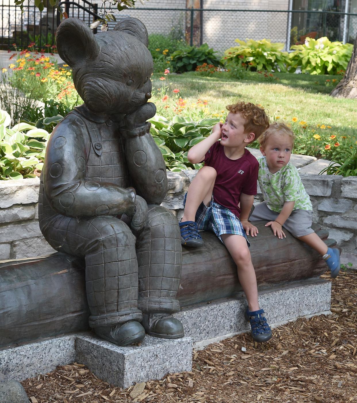 Constantine Northrop, 3, looks up at the Little Brown Bear statue outside the Dorsch Memorial Branch Library in downtown Monroe. His little brother Cyrus Northrop, 2, sits nearby. This year's summer reading program will highlight postcards in downtown Monroe businesses of Little Brown Bear's adventures.