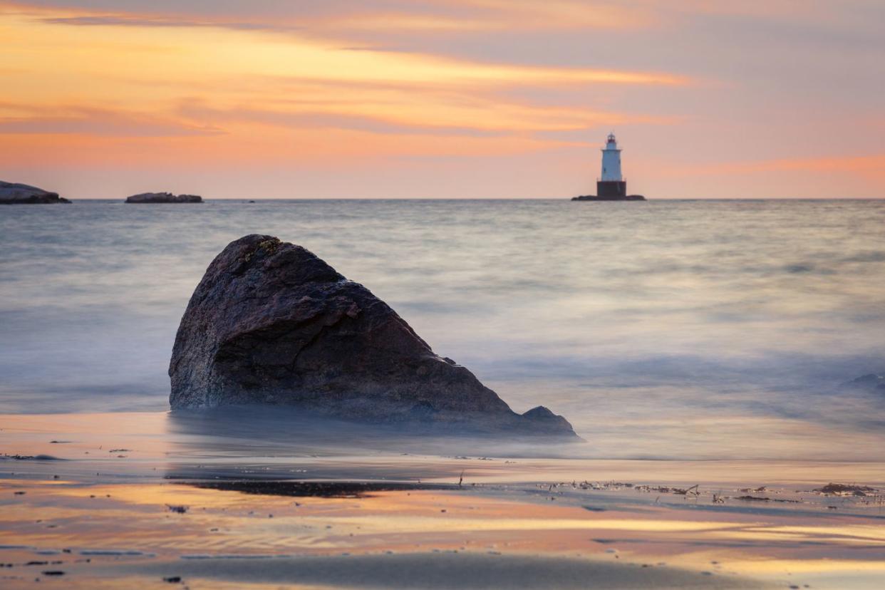 silky water rocky sunset seascape with lighthouse
