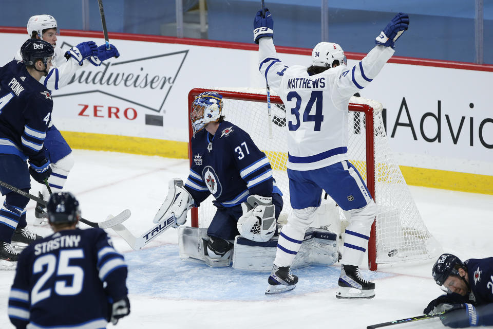 Toronto Maple Leafs' Auston Matthews (34) celebrates after scoring on Winnipeg Jets goaltender Connor Hellebuyck (37) during the first period of an NHL hockey game Wednesday, March 31, 2021, in Winnipeg, Manitoba. (John Woods/The Canadian Press via AP)