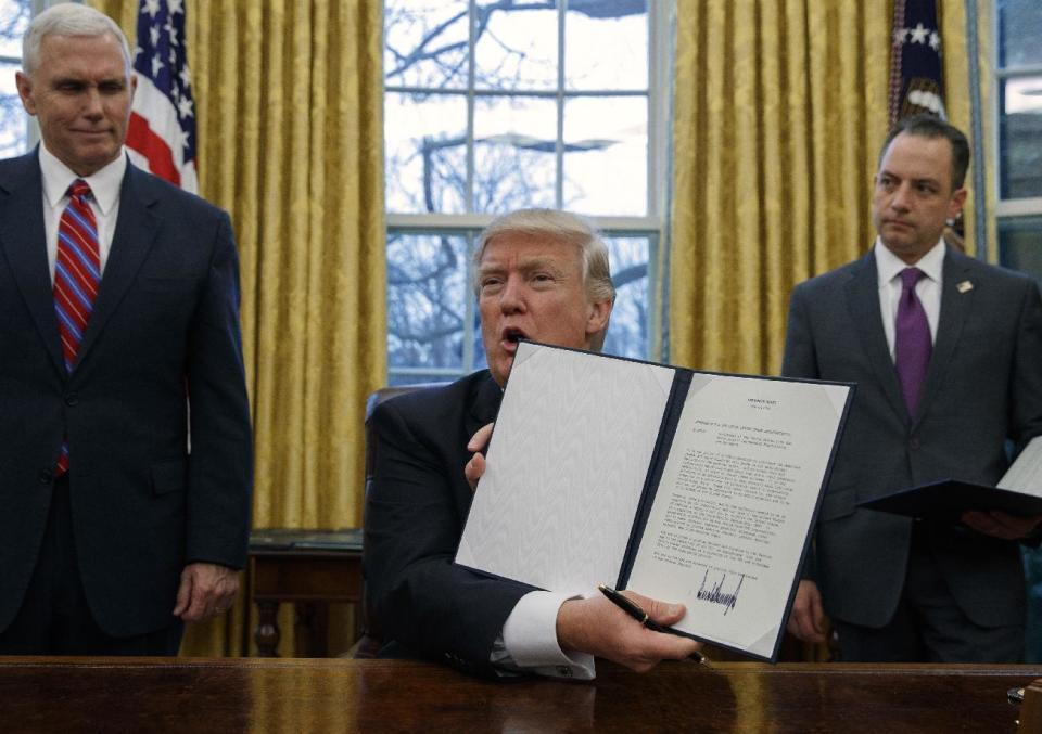 FILE - In this Monday, Jan. 23, 2017 file photo, Vice President Mike Pence, left, and White House Chief of Staff Reince Priebus, right, watch as President Donald Trump shows off an executive order to withdraw the U.S. from the 12-nation Trans-Pacific Partnership trade pact agreed to under the Obama administration in the Oval Office of the White House in Washington. Several countries expressed hope Tuesday, Jan. 24, that the Trans-Pacific Partnership could be salvaged, after President Donald Trump's decision on a U.S. withdrawal from the trade pact left its future in serious jeopardy. (AP Photo/Evan Vucci, File)