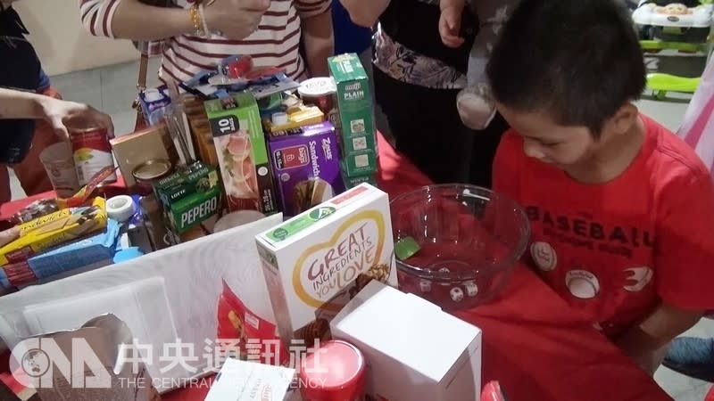 圖為馬尼拉一名華人小孩在彩品旁邊擲骰子。（中央社）