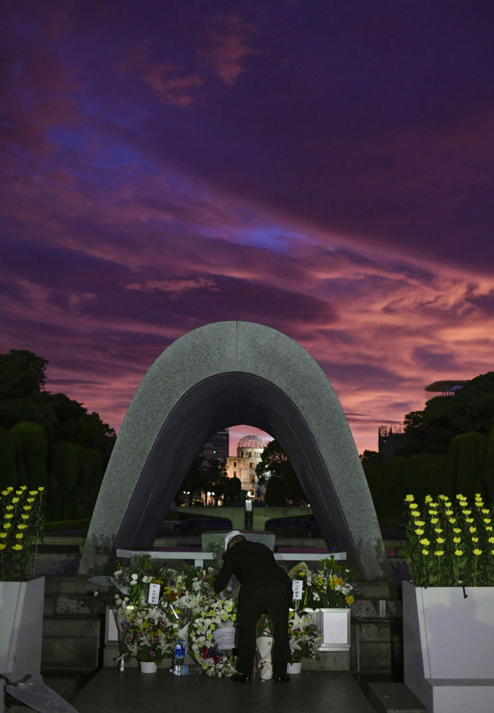 A man offers flowers for the atomic bomb victims in front of the cenotaph at the Hiroshima Peace Memorial Park in Hiroshima, western Japan during a ceremony to mark the 74th anniversary of the bombing early Tuesday, Aug. 6, 2019. (Kyodo News via AP)