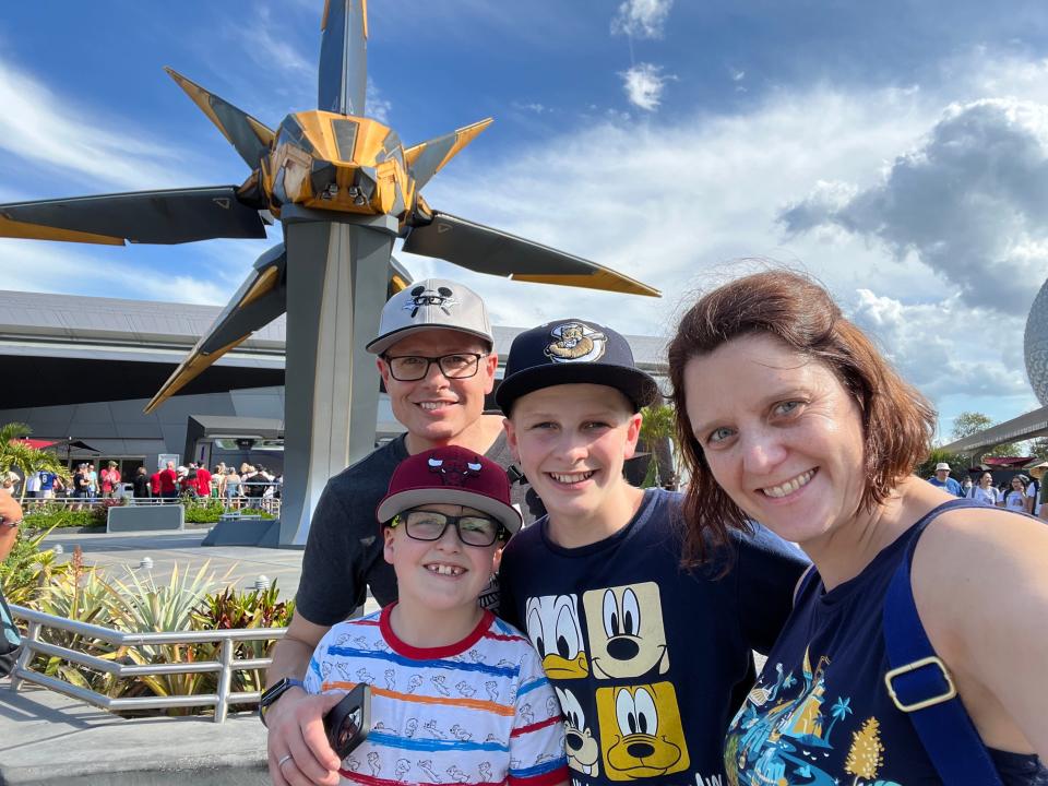 kari and her family posing for a selfie outside cosmic rewind coaster at epcot
